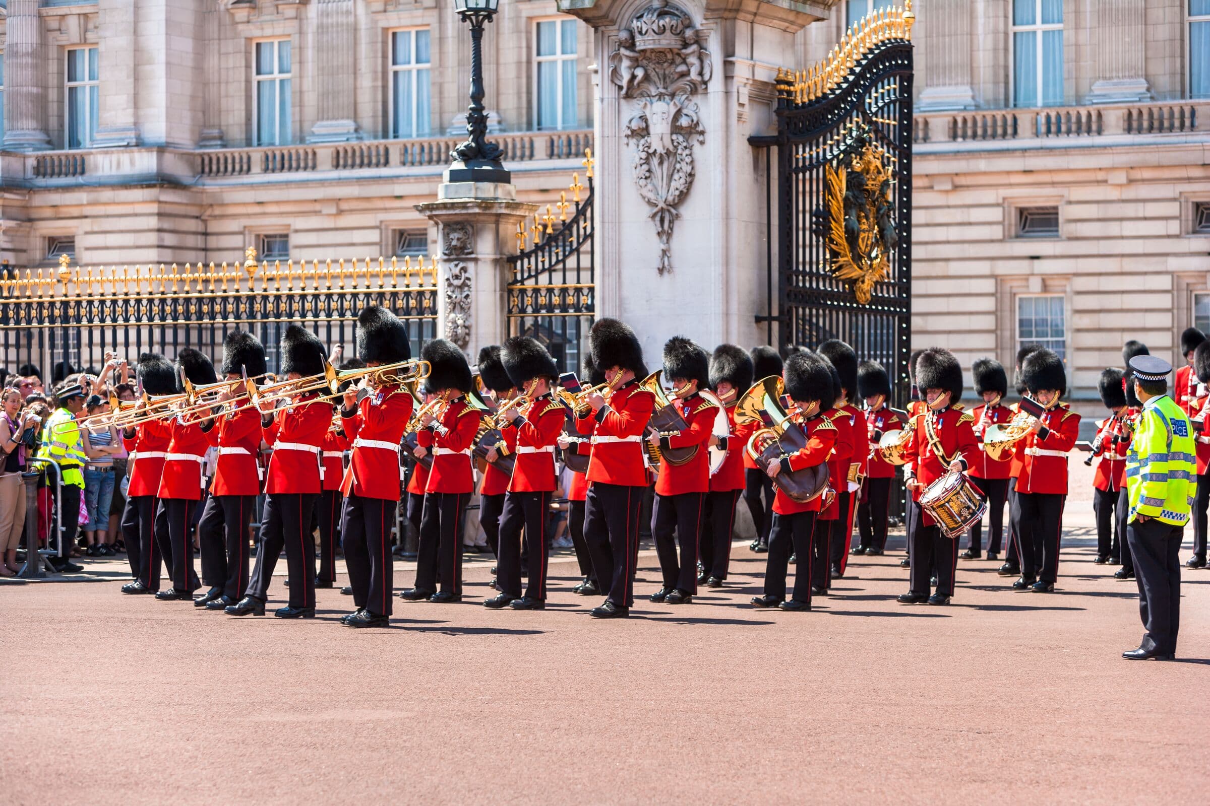 Guardsmen in red tunics marching outside Buckingham Palace